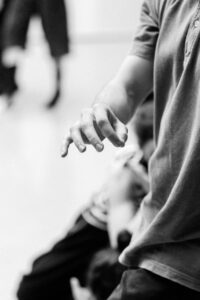 Close-up of dancers’ hands interacting during rehearsal, black and white
