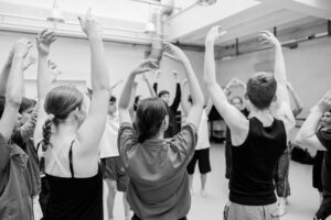 Contemporary dance rehearsal with multiple dancers interacting in a studio, black and white