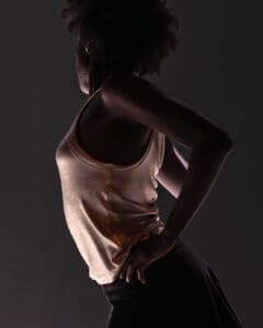 Close-up of a dancer in profile, body partially lit in a quiet and intimate stage moment.